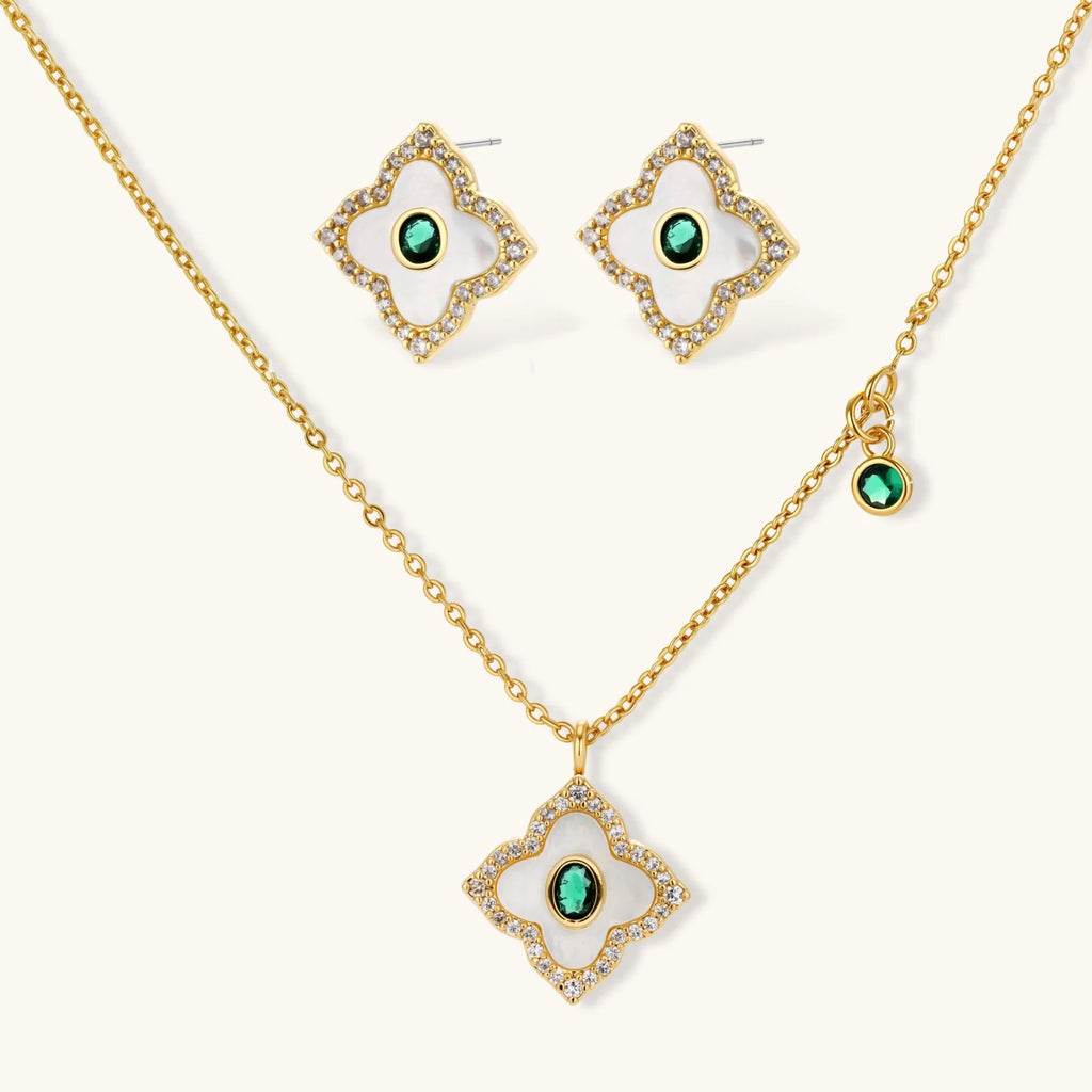 Emerald Bloom set: gold-tone pendant necklace and four-petal stud earrings with white inlay, oval green center stones and clear stone borders, front view