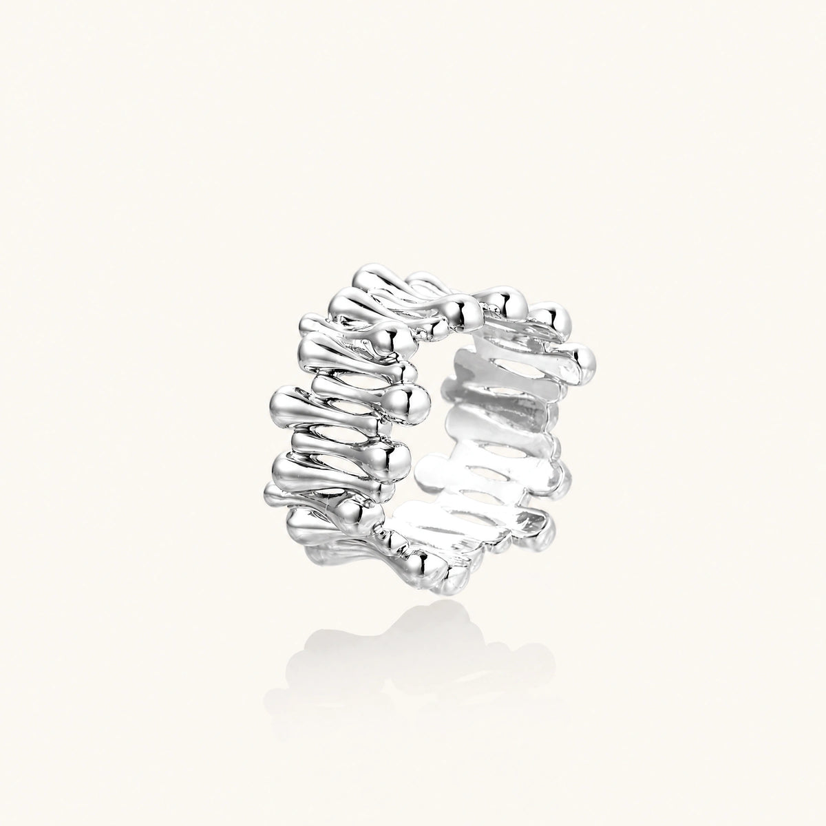 Wide band ring with sculptural wave ripples in polished white gold plated eco-brass on cream background
