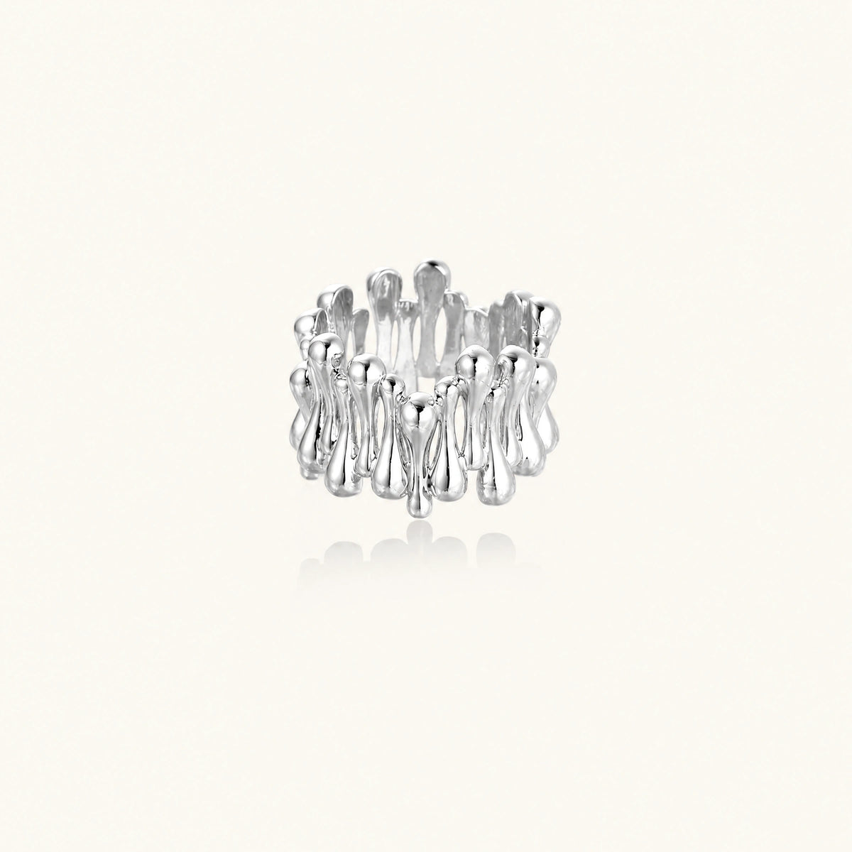 Wide band ring with sculptural wave ripples in polished white gold plated eco-brass on cream background