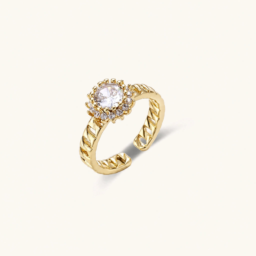 Gold-plated adjustable ring with twisted chain band, central cubic zirconia stone surrounded by crystal halo on cream background