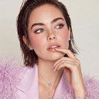 Model in a pink feathered jacket wearing the Pink Ribbon Cross necklace and earrings