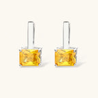 Front view of the Solar Duo drop hoop earrings with yellow and clear square stones