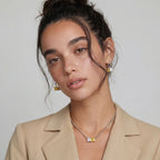 Model in a beige blazer wearing the Solar Duo necklace and earrings