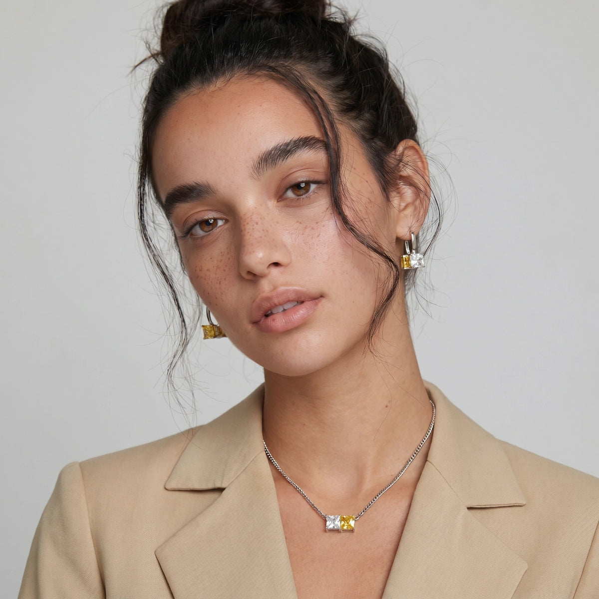 Model in a beige blazer wearing the Solar Duo necklace and earrings